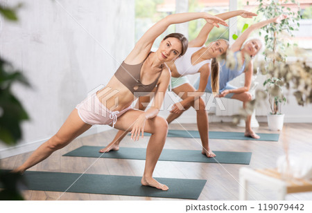 Young woman doing Utthita Parsvakonasana asana in yoga studio Young woman doing Utthita Parsvakonasana asana in yoga studio 119079442