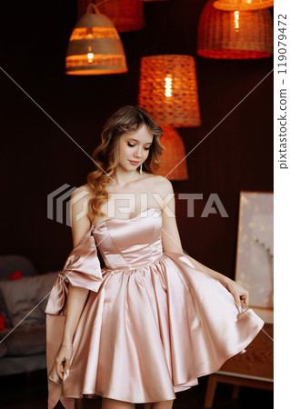 Woman in pink dress posing in Christmas interior with wooden furniture. 119079472