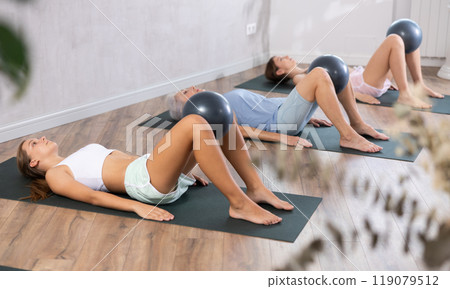 Teenage girl exercising with ball during group workout 119079512