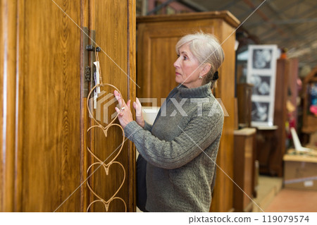 Elderly woman looking for wooden wardrobe in furnishing store Elderly woman looking for wooden wardrobe in furnishing store 119079574