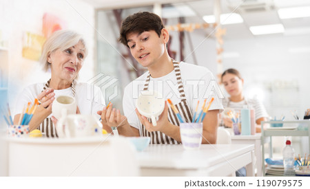 Cheerful guy working with elderly mother in family pottery studio 119079575