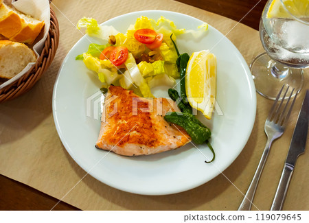 Roasted salmon steak with a light vegetable salad 119079645