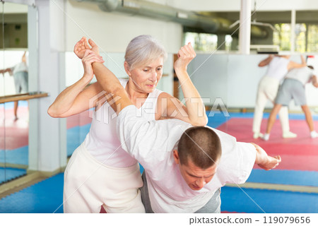Woman self defense training gym learning to do painful grip Woman self defense training gym learning to do painful grip 119079656