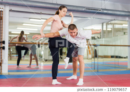 Girl with male opponent practicing elbow and knee strikes while locking arm 119079657
