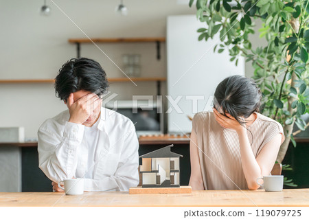 一對年輕夫婦正在查看房屋模型並考慮房屋的平面圖（遺憾、失敗、遺憾、維護成本、稅收） 119079725