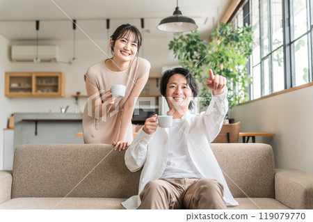 一對年輕的日本夫婦是親密的朋友，他們在自家客廳的沙發上聊天 119079770