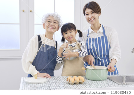 Three generations of women cooking in the kitchen: grandmother, mother, grandchild, looking at camera Three generations of women cooking in the kitchen: grandmother, mother, grandchild, looking at camera 119080480