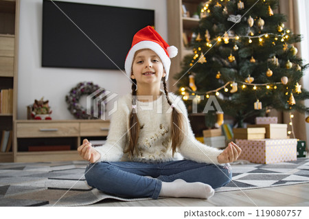 Young girl meditating in Santa hat by Christmas tree Young girl meditating in Santa hat by Christmas tree 119080757