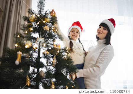 Mother and daughter decorating Christmas tree with joy 119080784