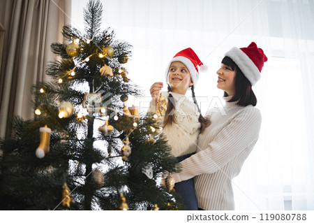 Mother and daughter decorating Christmas tree at home 119080788