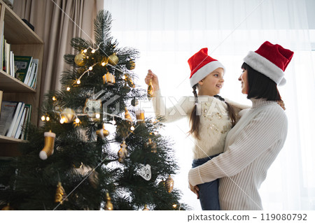 Mother and daughter decorating Christmas tree with joy Mother and daughter decorating Christmas tree with joy 119080792