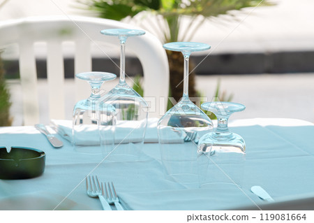 Upside-down wine glasses on an outdoor table 119081664