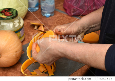 A woman cleans a pumpkin for cooking. A woman cleans a pumpkin for cooking. 119082347