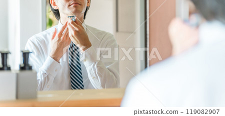 Young Asian businessman in a suit shaving in the bathroom before going to work in the morning Young Asian businessman in a suit shaving in the bathroom before going to work in the morning 119082907