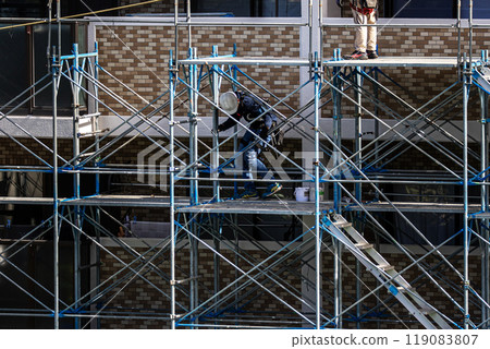 工匠在大型公寓維修工地搭建鷹架,安全第一。 工匠在大型公寓維修工地搭建鷹架,安全第一。 119083807