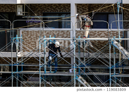 工匠在大型公寓維修工地搭建鷹架,安全第一。 工匠在大型公寓維修工地搭建鷹架,安全第一。 119083809