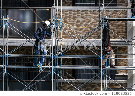 工匠在大型公寓維修工地搭建鷹架,安全第一。 工匠在大型公寓維修工地搭建鷹架,安全第一。 119083825