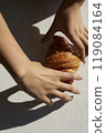 Hands and one croissant on white table with hard light 119084164