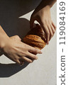 Hands and one croissant on white table with hard light 119084169
