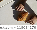 Hands and one croissant on white table with hard light 119084170