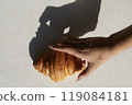 Hands and one croissant on white table with hard light 119084181
