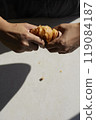 Hands and one croissant on white table with hard light 119084187