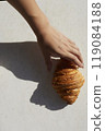 Hands and one croissant on white table with hard light 119084188
