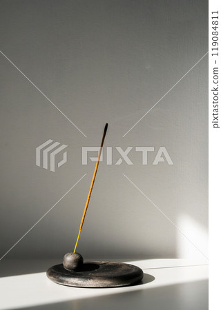 Burning incense stick and smoke with contrast shadows. Burning incense stick and smoke with contrast shadows. 119084811