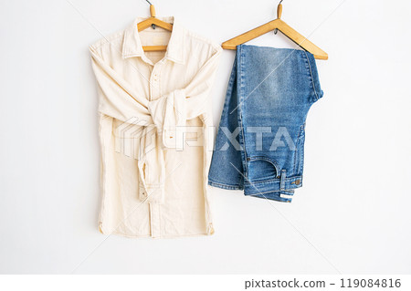 Shirt and jeans hanging on wooden hangers. Casual fashion concept. 119084816