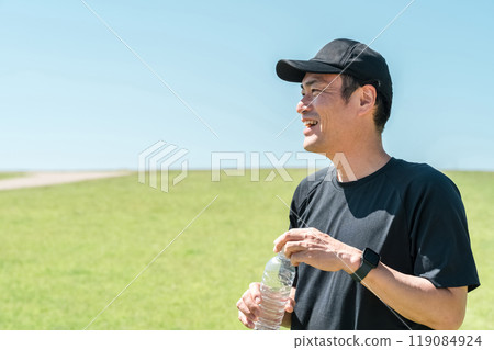 A man drinking water/mineral water during exercise (hydration, exercise, workout, running, walking) 119084924