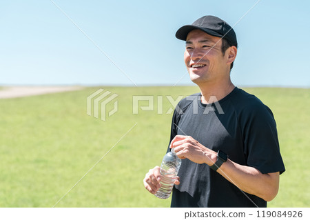 A man drinking water/mineral water during exercise (hydration, exercise, workout, running, walking) 119084926