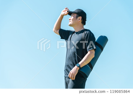 Asian man in sportswear holding yoga mat with empty bag 119085864