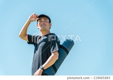 Asian man in sportswear holding yoga mat with empty bag Asian man in sportswear holding yoga mat with empty bag 119085865