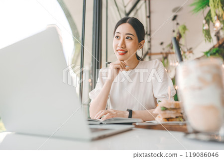 Adult business asian woman thinking for idea writing daily journal at indoors cafe 119086046