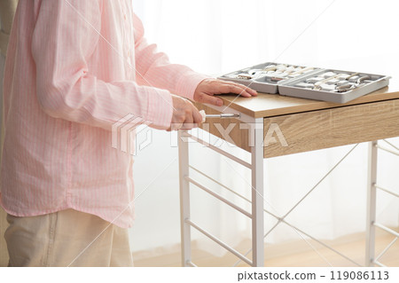 Middle-aged woman assembling a new kitchen rack Middle-aged woman assembling a new kitchen rack 119086113