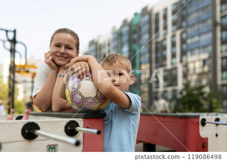 A mother and son enjoying quality time at a playground, sharing laughter and bonding over a soccer 119086498