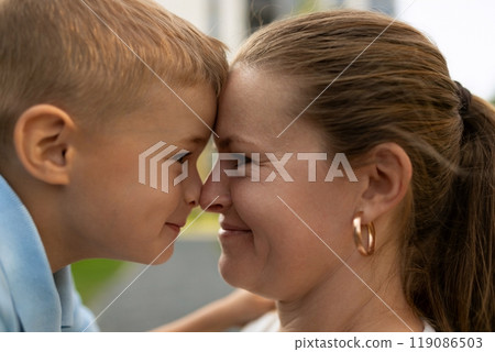 A joyful moment between a mother and her young son outdoors during a sunny day in a park 119086503