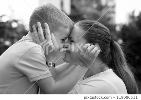 A joyful moment of connection and affection between a mother and her young son outdoors in a loving 119086511
