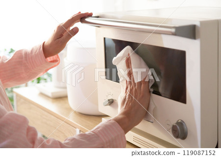 The hands of a middle-aged woman cleaning a microwave oven 119087152
