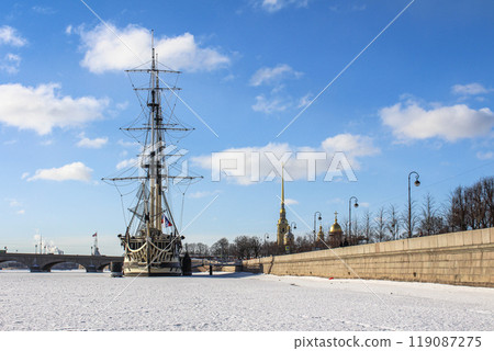 Winter view of the frozen Neva River with a historic ship and the Peter and Paul Fortress in Saint Petersburg, Russia 119087275