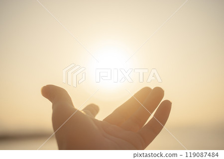 Hands stretched out towards the sunset 119087484