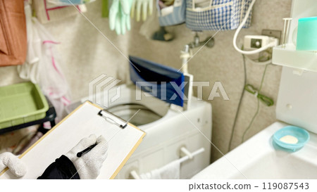 手戴工作手套,拿著剪貼板,評估洗衣機周圍的區域 手戴工作手套,拿著剪貼板,評估洗衣機周圍的區域 119087543