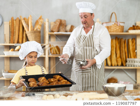 Family bakery - father showing girl baked hot croissants on tray 119087797