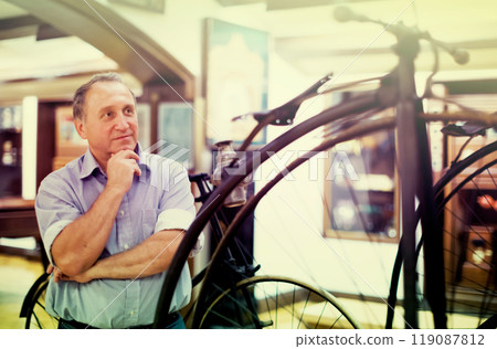 Mature man examines the exhibit in museum 119087812