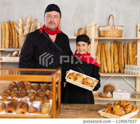 Father baker poses with his little daughter in black chef uniform with red scarf tied around her neck Father baker poses with his little daughter in black chef uniform with red scarf tied around her neck 119087837
