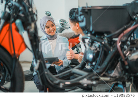 veiled shop assistant using a laptop serves buyers in a showroom veiled shop assistant using a laptop serves buyers in a showroom 119088576