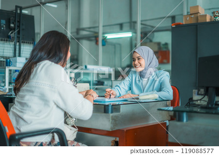 veiled female shop assistant serves a customer about loan installment veiled female shop assistant serves a customer about loan installment 119088577