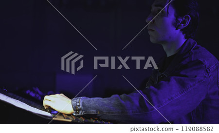 Technician works at stage console. Media. Young man is working at console of modern stage. Stage light and sound control panel 119088582