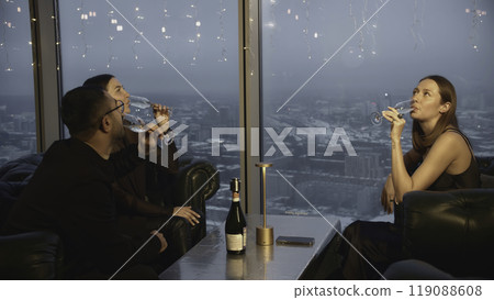 Friends clink glasses of champagne and drink in restaurant. Media. Friends drink champagne and relax in restaurant overlooking city. Evening meeting of friends with champagne in elegant restaurant Friends clink glasses of champagne and drink in restaurant. Media. Friends drink champagne and relax in restaurant overlooking city. Evening meeting of friends with champagne in elegant restaurant 119088608