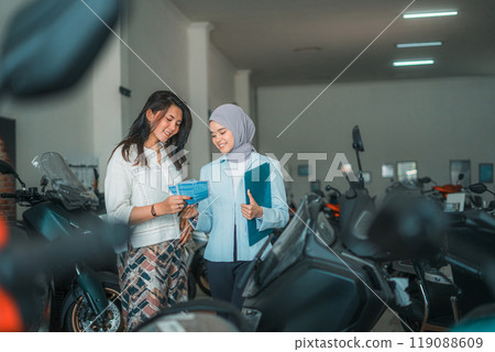 female visitor and saleswoman chatting about a new motorcycle female visitor and saleswoman chatting about a new motorcycle 119088609